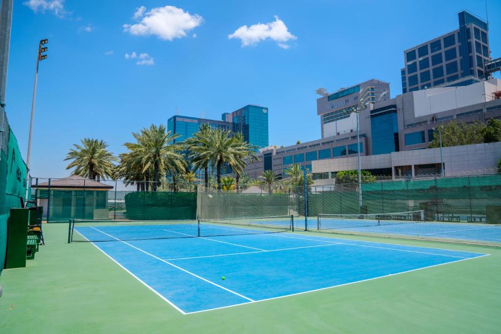 a tennis court with palm trees and buildings at Beach Rotana - Abu Dhabi in Abu Dhabi