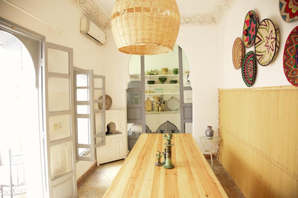 a dining room with a wooden table and a chandelier at Riad Dar Wildeve in Marrakesh