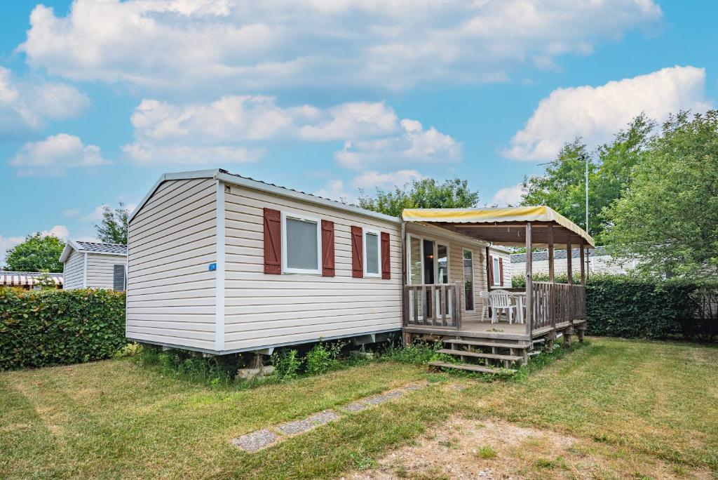 a small white tiny house with a porch at Mobil-home Elegance - 3 chambres in Seillac