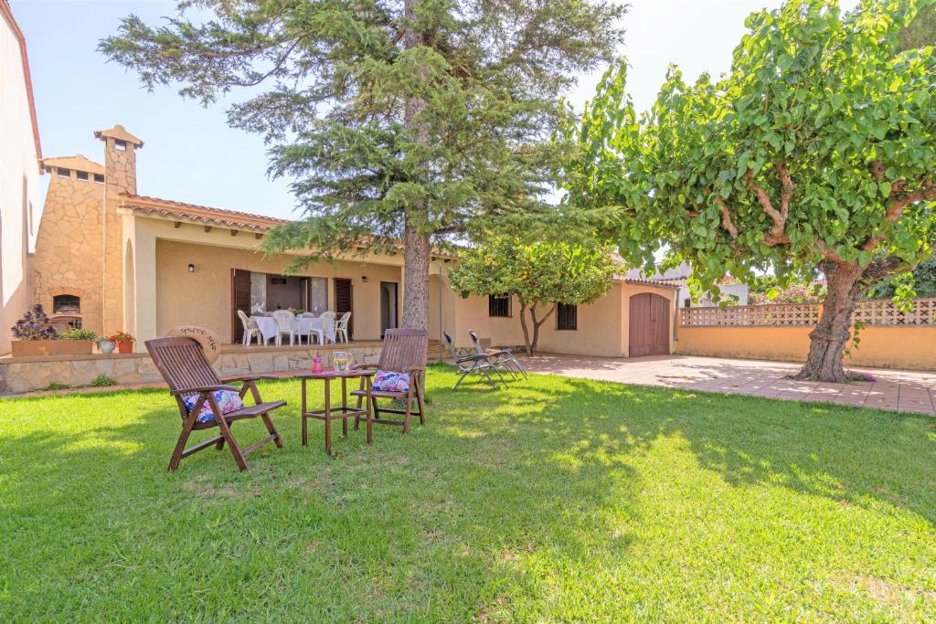 un cortile con sedie e tavolo di fronte a una casa di Apart-rent Casa con jardín Pani 0081 a Empuriabrava