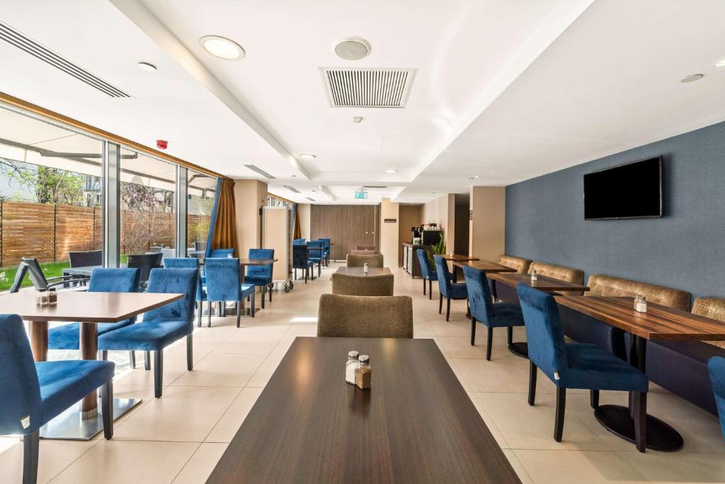 a dining room with tables and blue chairs at Hampton by Hilton Cluj-Napoca in Cluj-Napoca