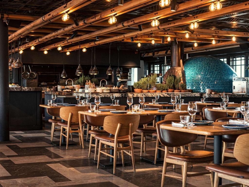 a restaurant with wooden tables and chairs and lights at Novotel Istanbul Bosphorus Hotel in Istanbul