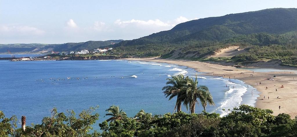 a beach with palm trees and people on the beach at La View 麗晨 Homestay in Manzhou
