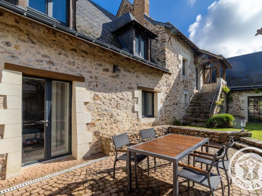 eine Terrasse mit Tisch und Stühlen vor einem Gebäude in der Unterkunft Chambre d'hôtes avec piscine et petit-déjeuner proche d'Angers - FR-1-622-84 in La Rochefoulques