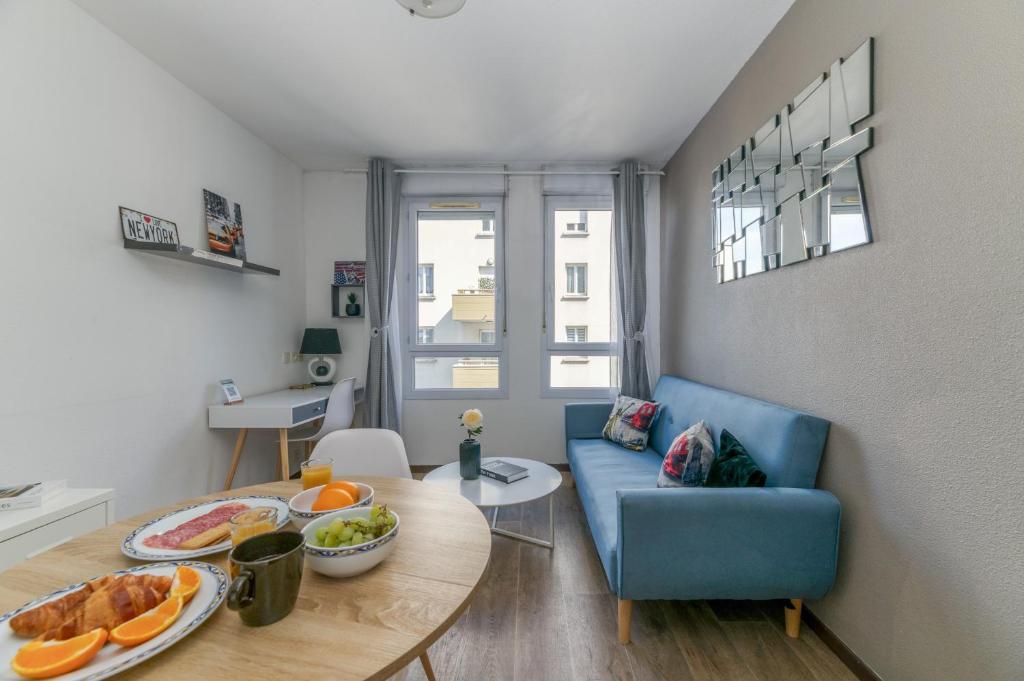 un salon avec un canapé bleu et une table dans l'établissement R'Apparts T2 Le New York, à Grenoble