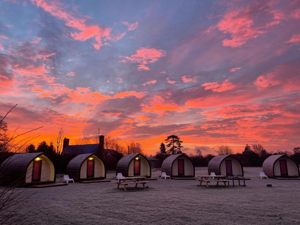 a group of domes and picnic tables under a sunset at Rodway Hill Golf & Eco Pod Hotel in Gloucester