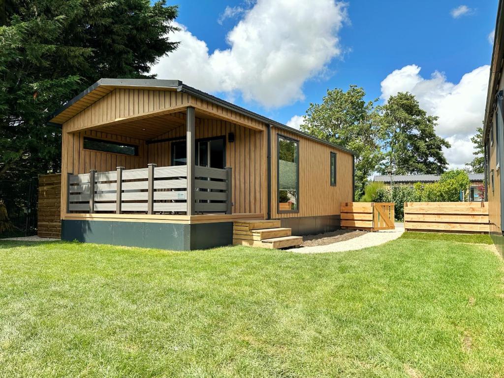 a small wooden building with a grass yard at Chalet 501a op Recreatiepark De Wielen in Sint Maarten