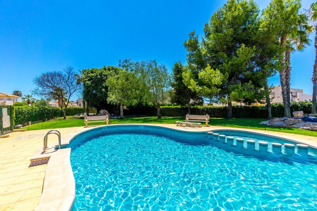 een zwembad met twee banken in een tuin bij HE La Florida-David in Orihuela-Costa