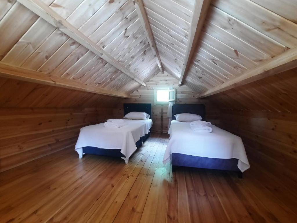 two beds in a room with a wooden ceiling at Adrasan Eren Apart evleri in Adrasan