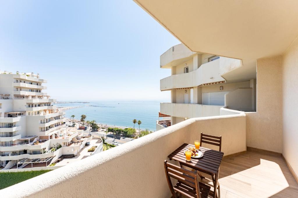 a balcony with a table and chairs and a view of the ocean at BENALBEACH Apartamento Exclusivo in Benalmádena