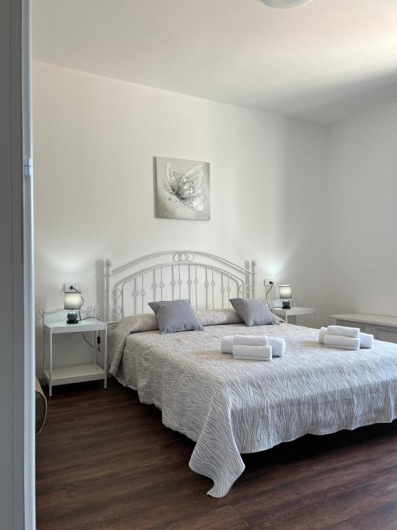 a white bedroom with a large bed with two pillows at Harmony Affittacamere in Tortolì