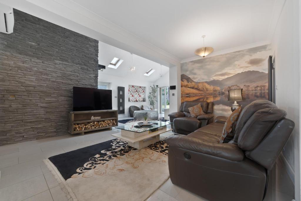 a living room with a couch and a tv at 3 Bedroom Bungalow Sunningdale Lodge Ascot Races in Sunningdale