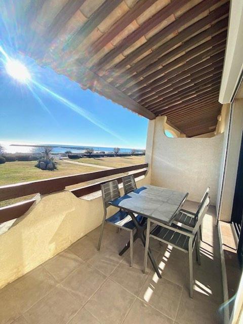 une table et des chaises sur un balcon avec vue sur l'océan dans l'établissement Appartement vue mer B21, parking privé, à Saintes-Maries-de-la-Mer