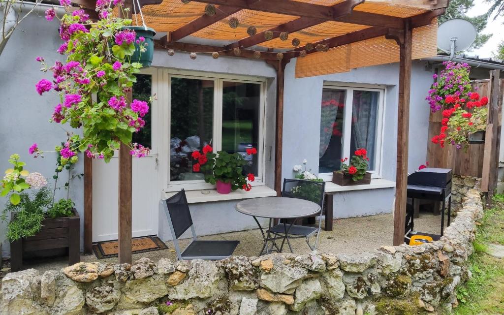 une terrasse d'une maison avec une table et des fleurs dans l'établissement Petit cottage, à Saint-Pierre-la-Garenne