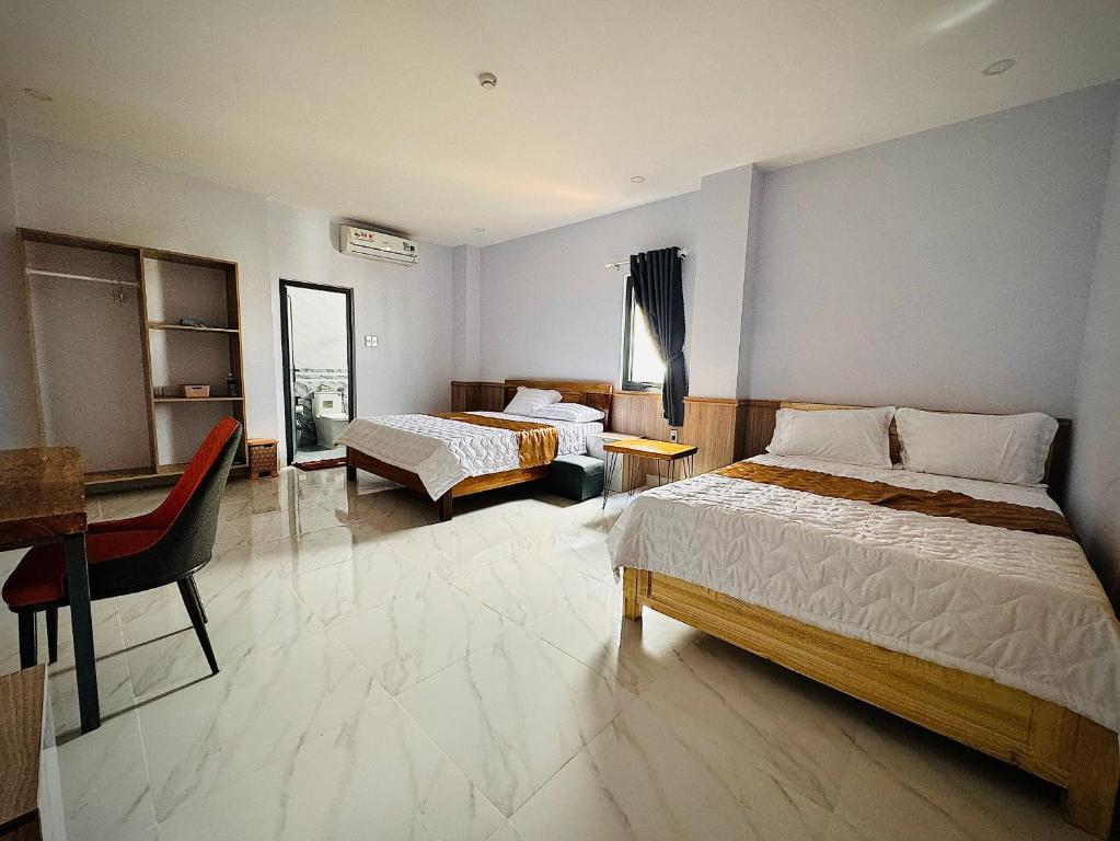 ein Hotelzimmer mit zwei Betten und einem Schreibtisch in der Unterkunft Khách Sạn Metro Ban Mê in Buon Ma Thuot