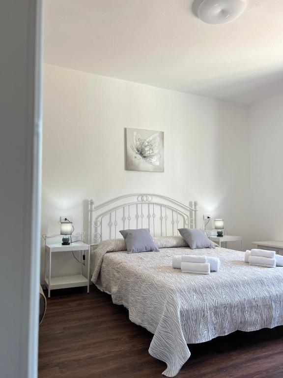a white bedroom with a large white bed with blue pillows at Harmony Affittacamere in Tortolì