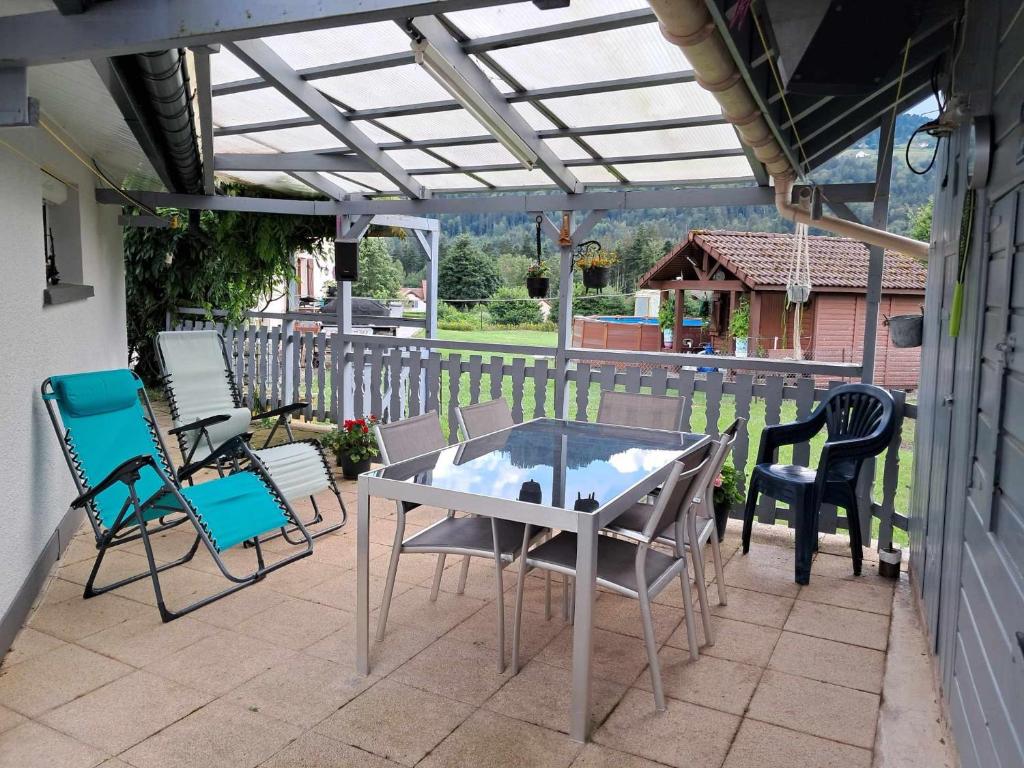 un patio avec une table et des chaises sur un porche dans l'établissement LE CROSERY Clim Rando Ski BBQ Voie Verte, à Thiéfosse