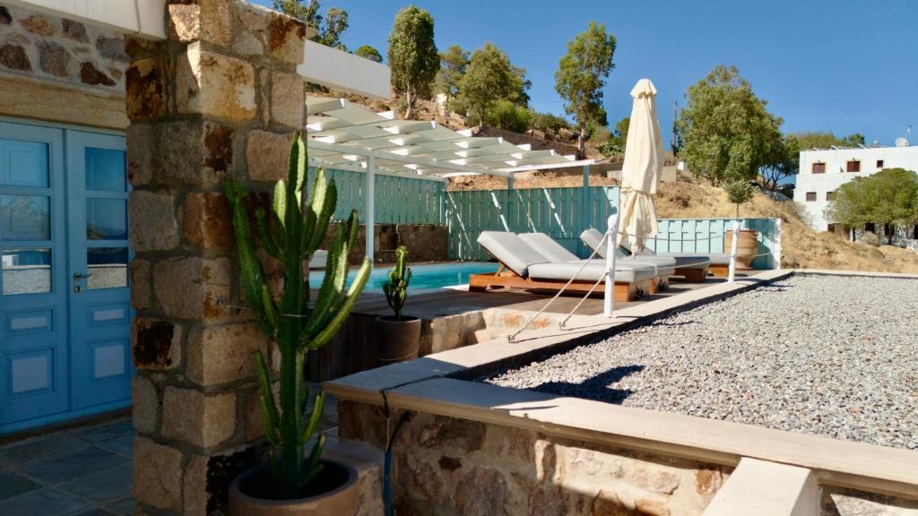 a patio with an umbrella and chairs and a pool at Theologos Houses in Grikos