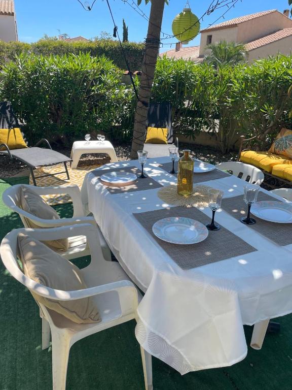 - une table blanche avec des assiettes blanches et des verres à vin dans l'établissement L'air marin, à Sigean