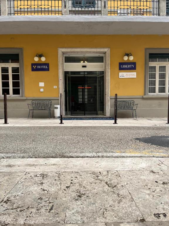 a building with two benches in front of it at Hotel Liberty in Montecatini Terme