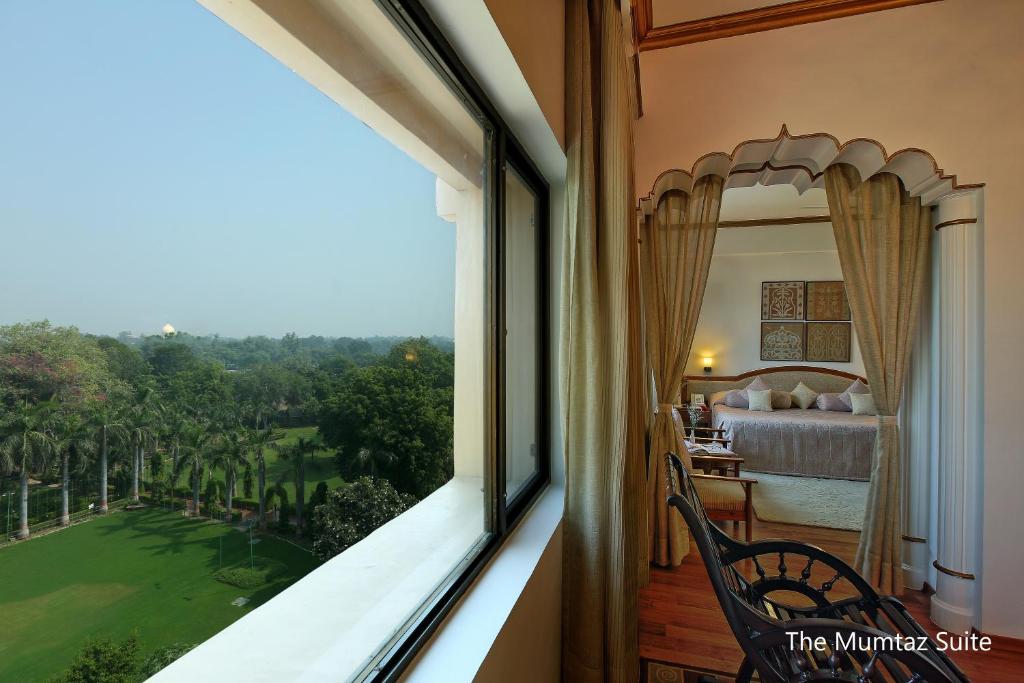 a bedroom with a view of a golf course from a window at Hotel Clarks Shiraz in Agra