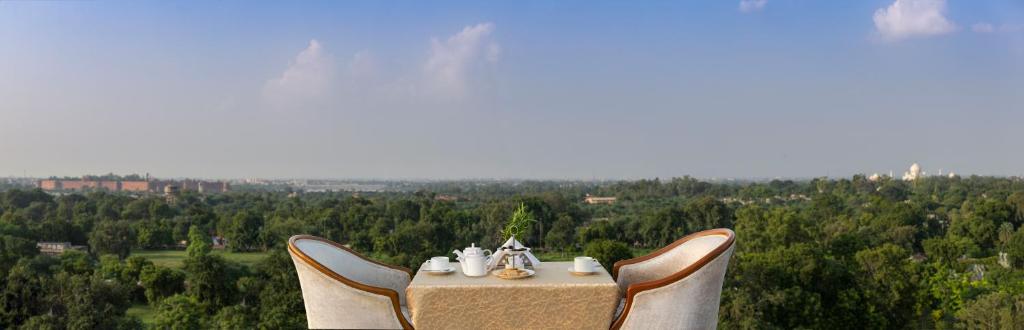 a table and two chairs with a table and a view at Hotel Clarks Shiraz in Agra