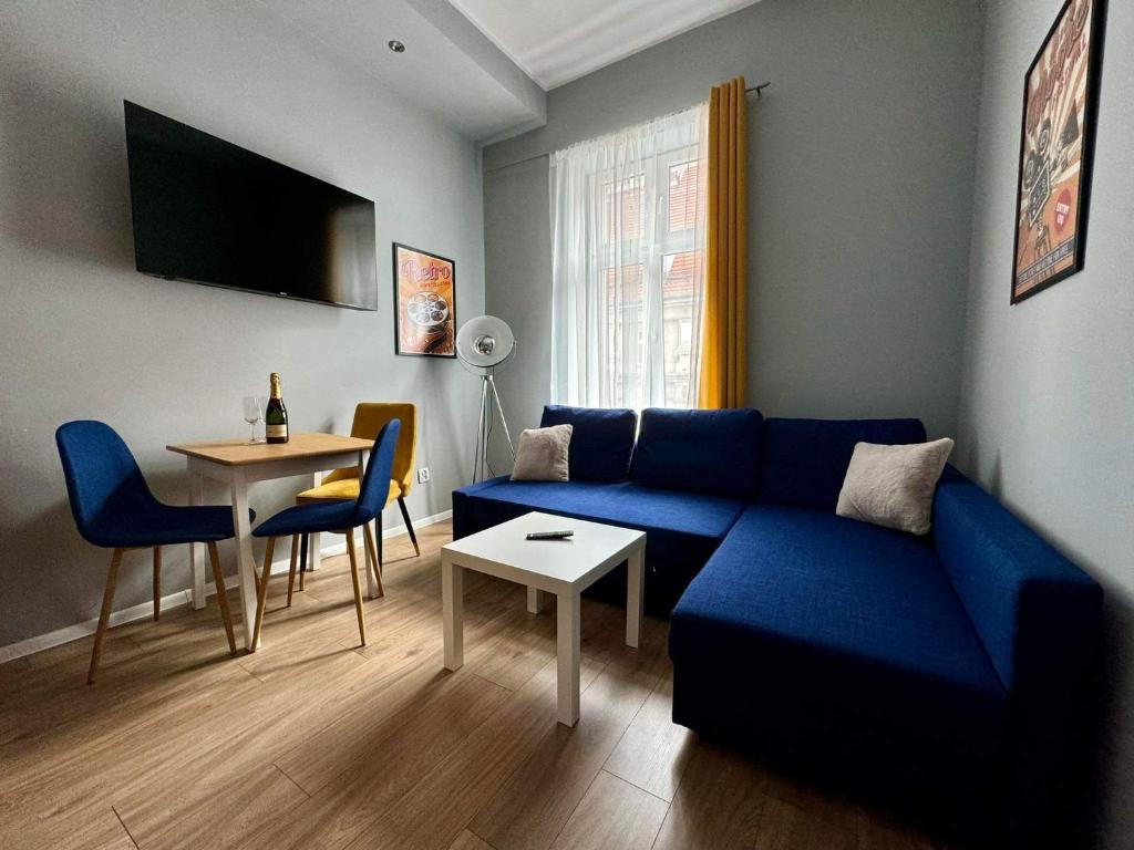 a living room with a blue couch and a table at Apartament Filmowy in Wałbrzych
