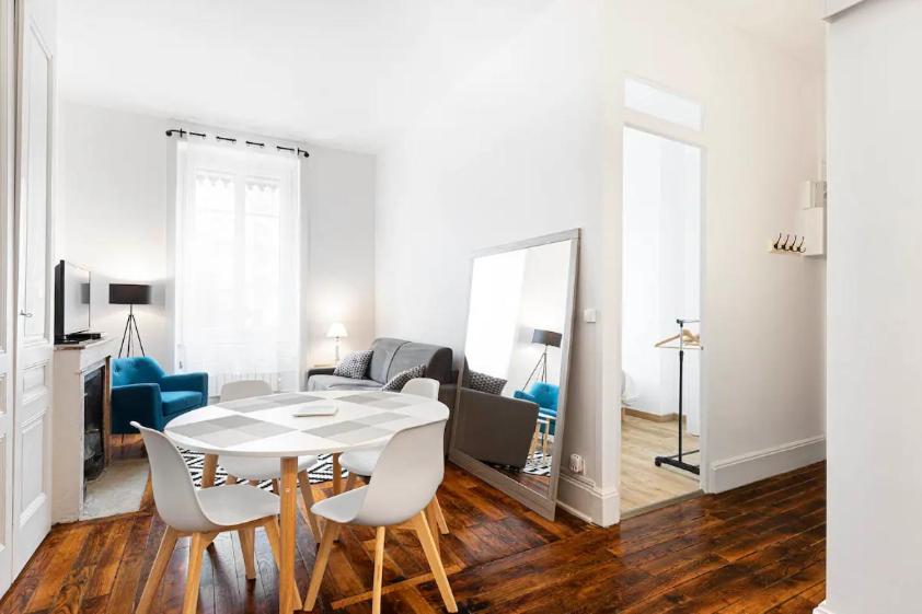 a white living room with a table and chairs at appartement 2 pièces Jean Macé et stationnement in Lyon