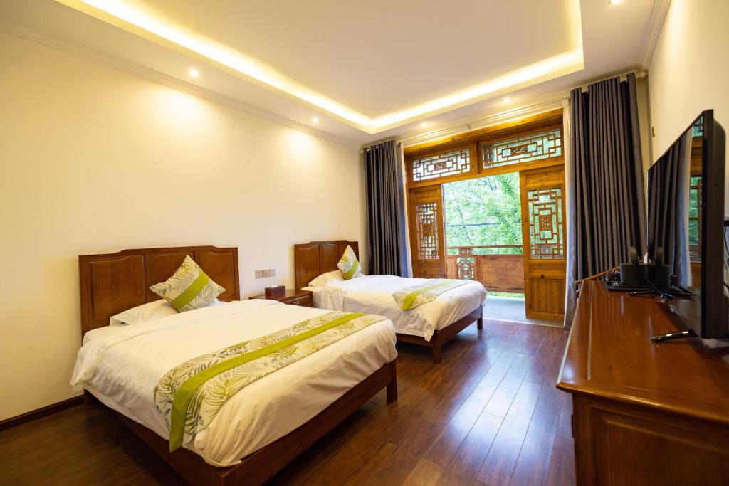 a hotel room with two beds and a television at 青城山泉青小院温泉中式民宿 in Taiping
