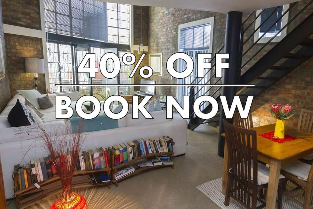 a book now sign in a living room with a bed and a table at Waterkant Loft in Cape Town