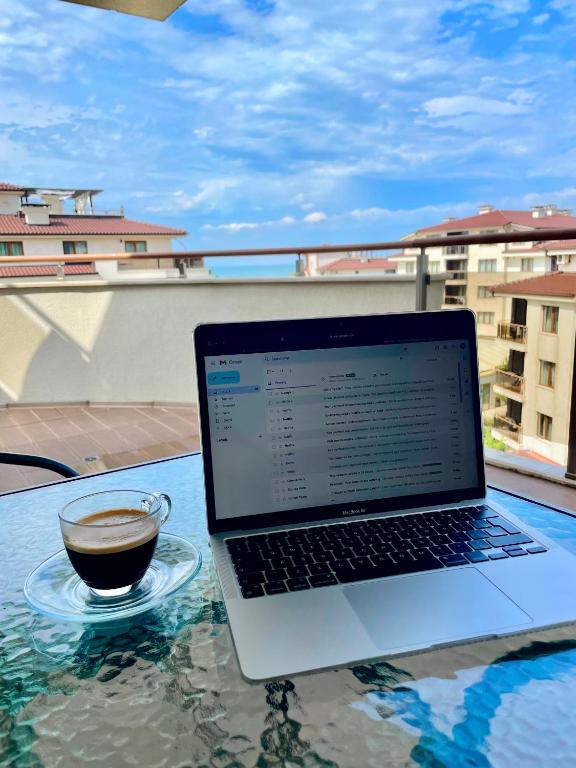 a laptop sitting on a table with a cup of coffee at Long Sunny Holiday in Shkorpilovtsi