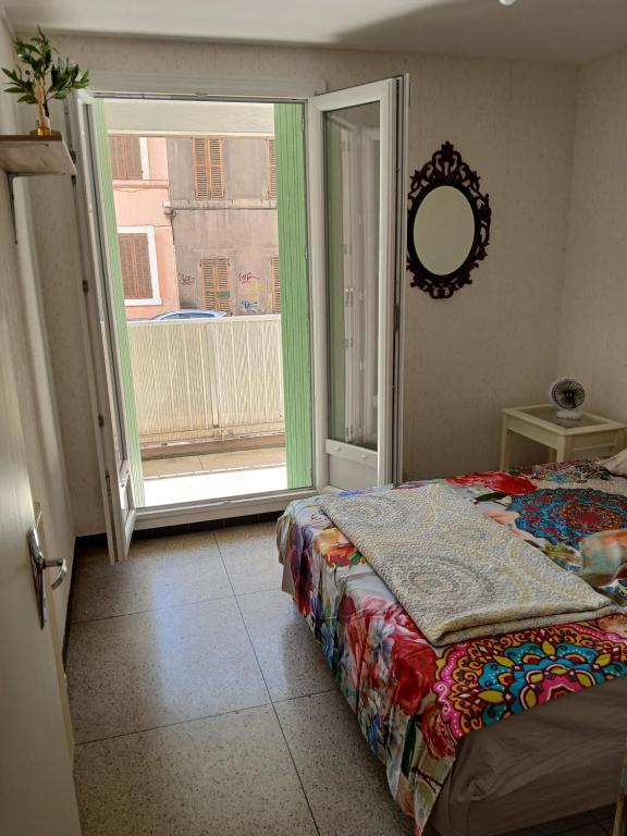 une chambre avec un lit et une grande fenêtre dans l'établissement Chambre avec balcon dans une appartement la belle de mai, à Marseille
