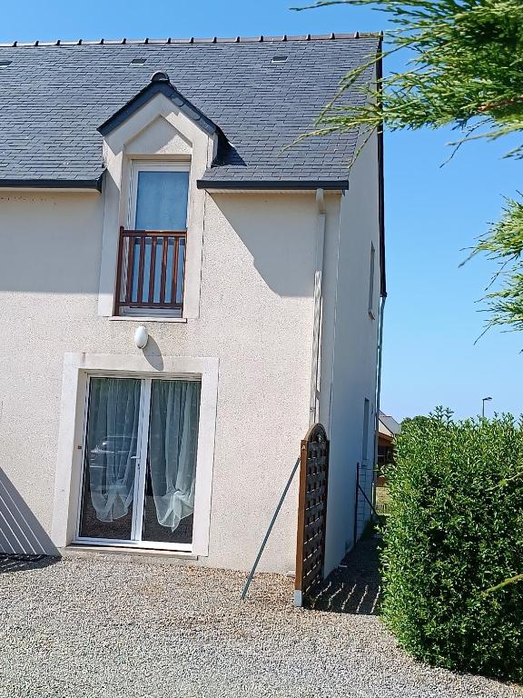 Cette maison blanche dispose d'une fenêtre et d'un balcon. dans l'établissement NOUVELLE VILLA d'EMERAUDE PROCHE MER, à Saint-Méloir-des-Ondes