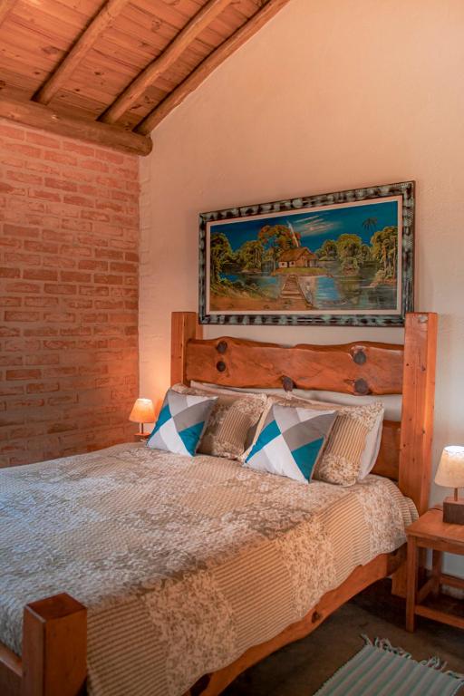 a bedroom with a large bed with a wooden headboard at Pousada Canto dos Pássaros in Santo Antônio do Pinhal