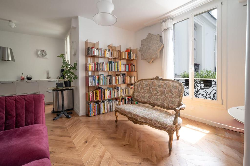 - un salon avec un canapé et une étagère avec des livres dans l'établissement Appartement Ottomane - Welkeys, à Paris