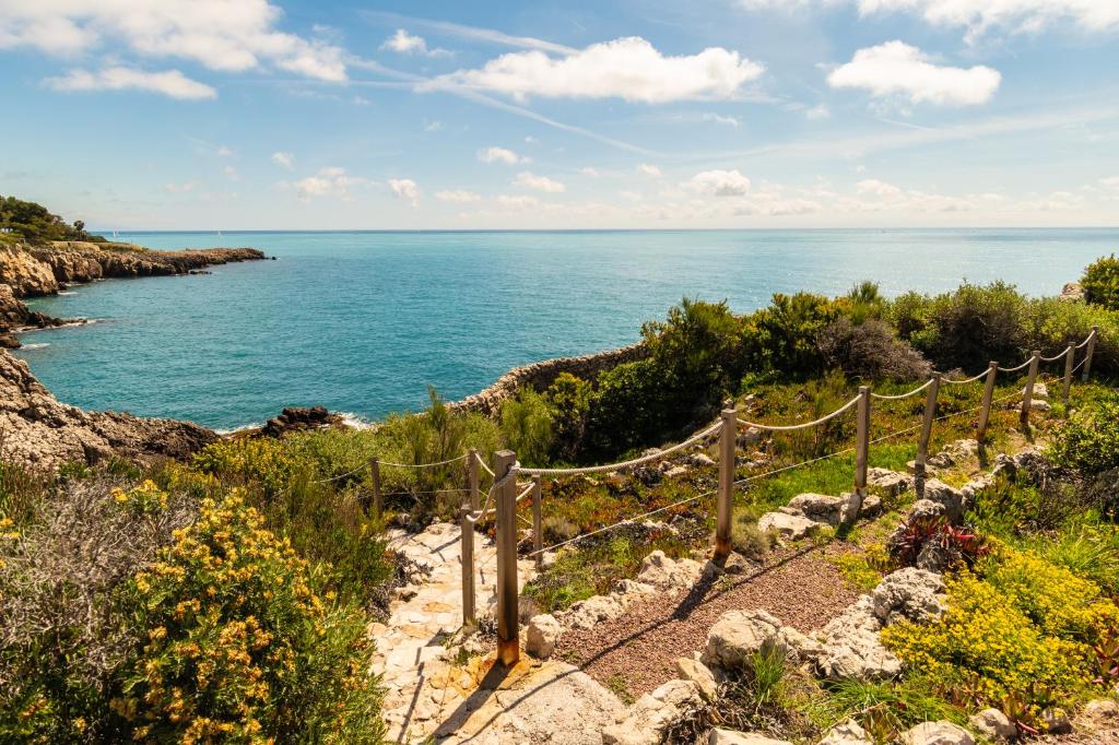 un chemin en bois menant à l'océan sur une falaise dans l'établissement Le Clochet du Cap D'Antibes Pavillion de 690m2 Tennis Piscine Spa Plage, à Juan-les-Pins