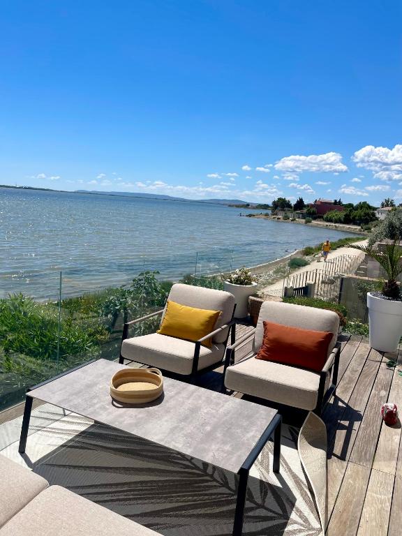 - deux chaises et une table avec vue sur l'eau dans l'établissement Design villa with panoramic pond view and jacuzzi, à Pérols