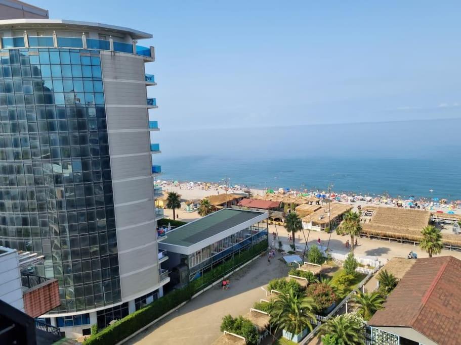a tall building next to a beach with the ocean at Mgzavrebi Apartments in Kvariati