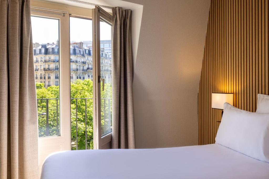 une chambre d'hôtel avec un lit et une grande fenêtre dans l'établissement Hotel Korner Montparnasse, à Paris
