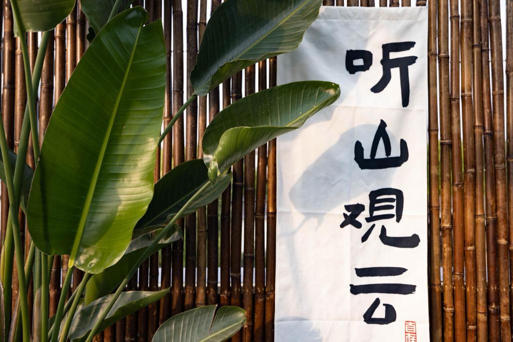 a sign with asian writing on a wall with a plant at 青城山泉青小院温泉中式民宿 in Taiping