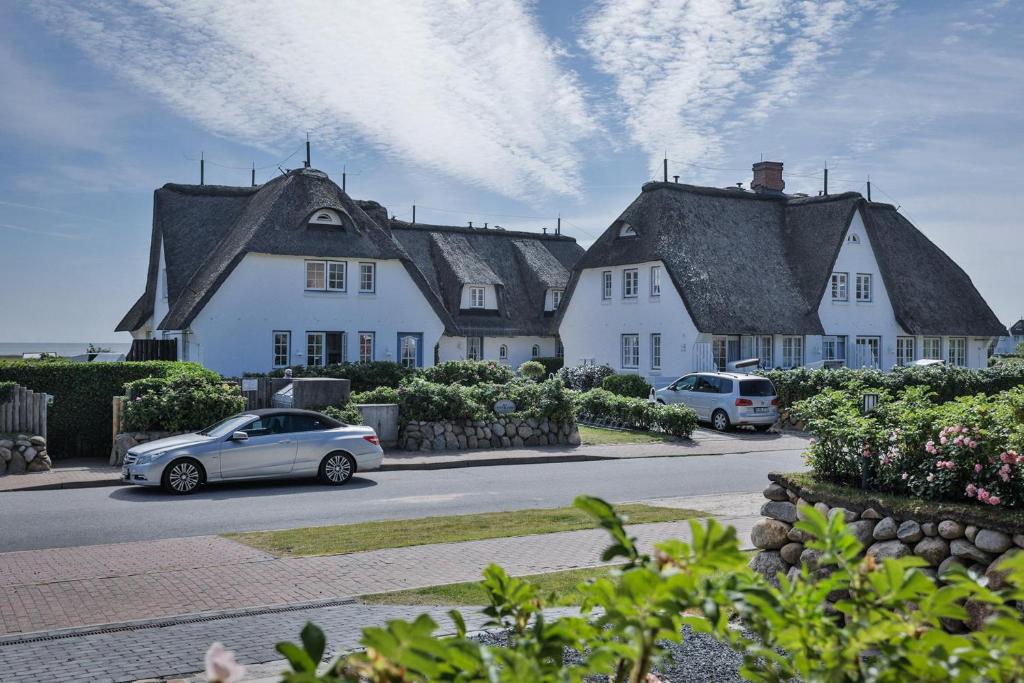 two cars are parked in front of a house at Söl'ring Hüs "kleiner traum rantum" in Rantum