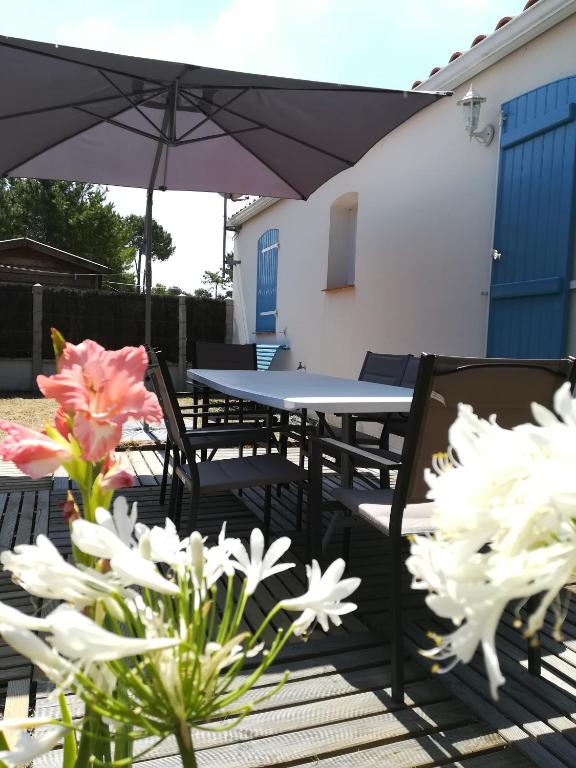 - une terrasse avec une table, des chaises et des fleurs dans l'établissement maison récente proche forêt et bord de mer, à Saint-Jean-de-Monts