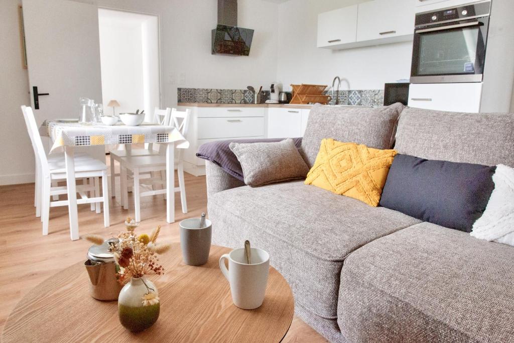 un salon avec un canapé gris et une table dans l'établissement À 230m de la plage - Bel appartement pour 4, à Fouesnant
