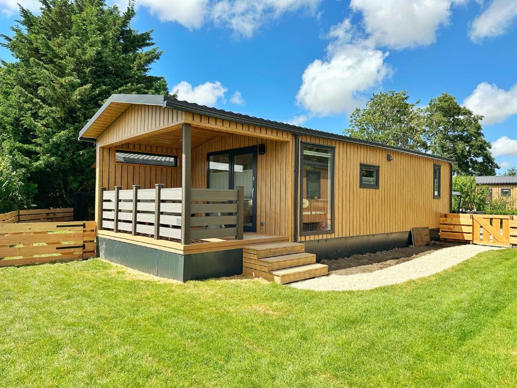 a small wooden cabin with a grassy yard at Chalet 501b op Recreatiepark De Wielen in Sint Maarten