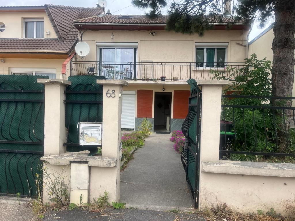 a house with a green fence and a driveway at Villa Jasmin in Bobigny