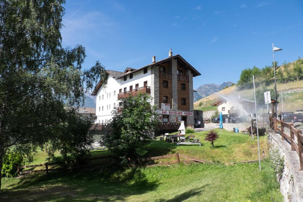 a building on a hill with a grassy field at Hotel & Restaurant Saint Nicolas Gran Paradiso in Saint Nicolas