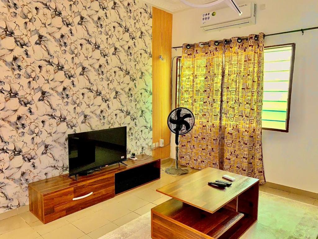 Una sala de estar con un televisor y una mesa. en Appartement Jito, en Cotonou