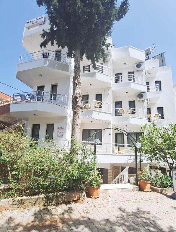 a white building with a tree in front of it at Golden Beach Hotel in Didim