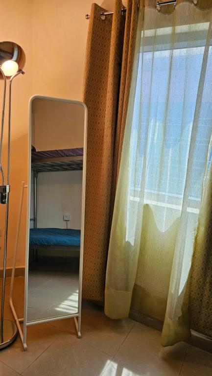 a mirror next to a window with a curtain at Hostel Faye in Abu Dhabi
