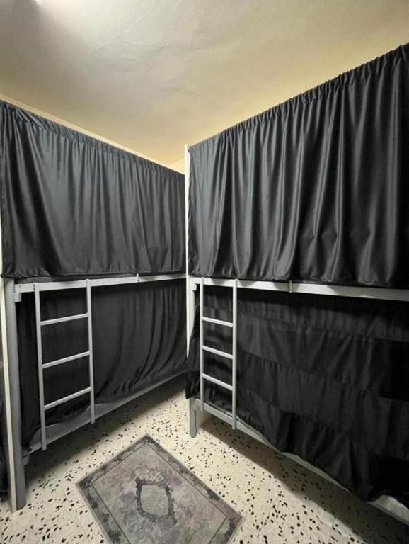 a room with two bunk beds with curtains and a rug at Hostel Faye in Abu Dhabi